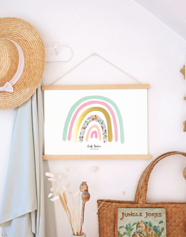 Liberty print personalised rainbow nursery art by The Charming Press displayed on wooden hanger in a nursery. 
