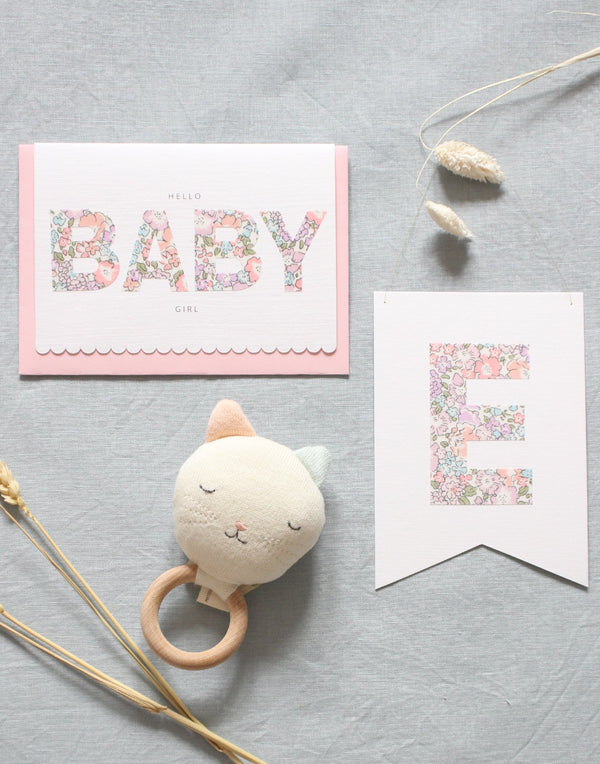 New baby gift card,  personalised Liberty print flag and cat rattle. Content of new baby girl gift box by The Charming Press. 