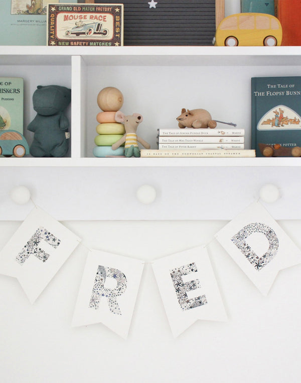 Liberty print personalised Bunting in Liberty print Starry fabric hanging on a nursery shelf.