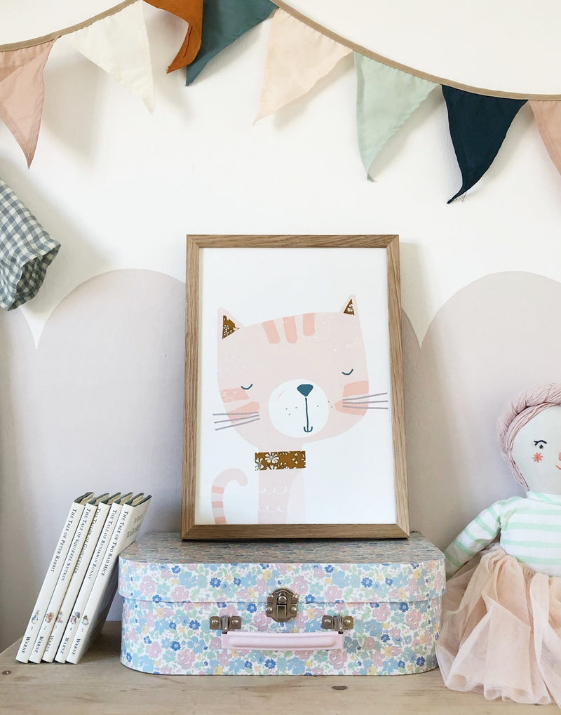 Cat nursery art by The Charming Press shown on top of a floral suitcase in child's bedroom.