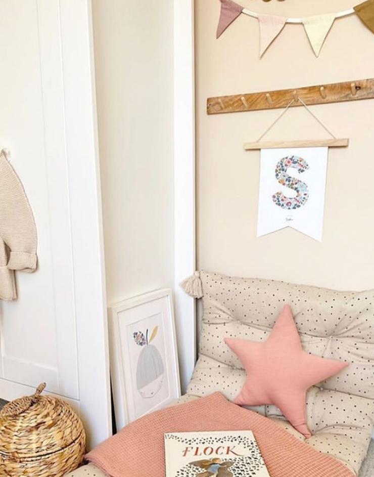 Child's bedroom scene showing a bed, hanging shelf with monogram nursery flag hanging and print from The Charming Press on the floor.