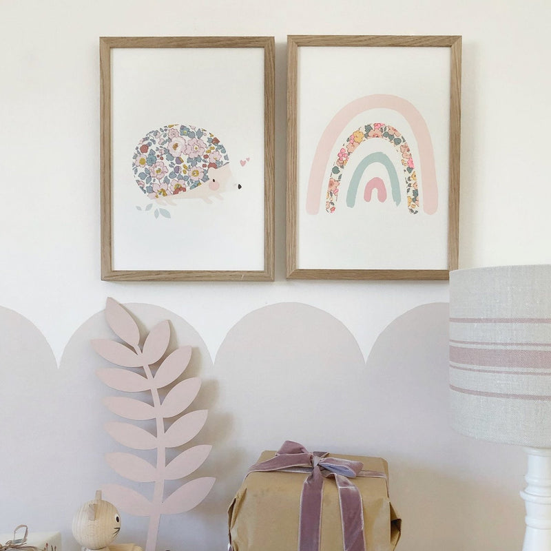 Children's playroom gallery wall with Liberty print hedgehog and rainbow art.