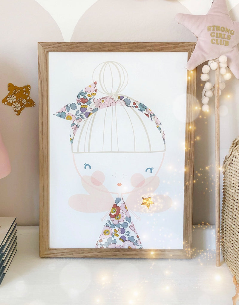 Kids' wall art featuring a fairy with Liberty print and glitter details by The Charming Press shown on shelf.