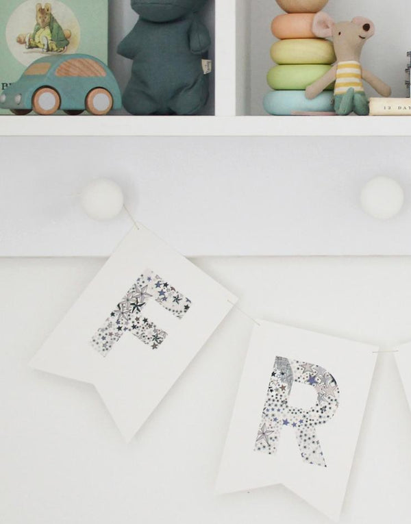 Personalised Liberty name bunting hanging on shelf in child's nursery.