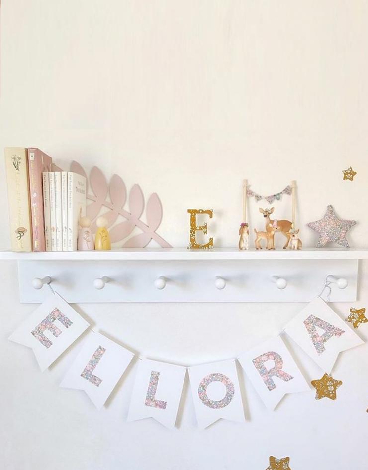  Bunting personalised with child's name in Liberty Michelle Lilac fabric hanging on nursery shelf.