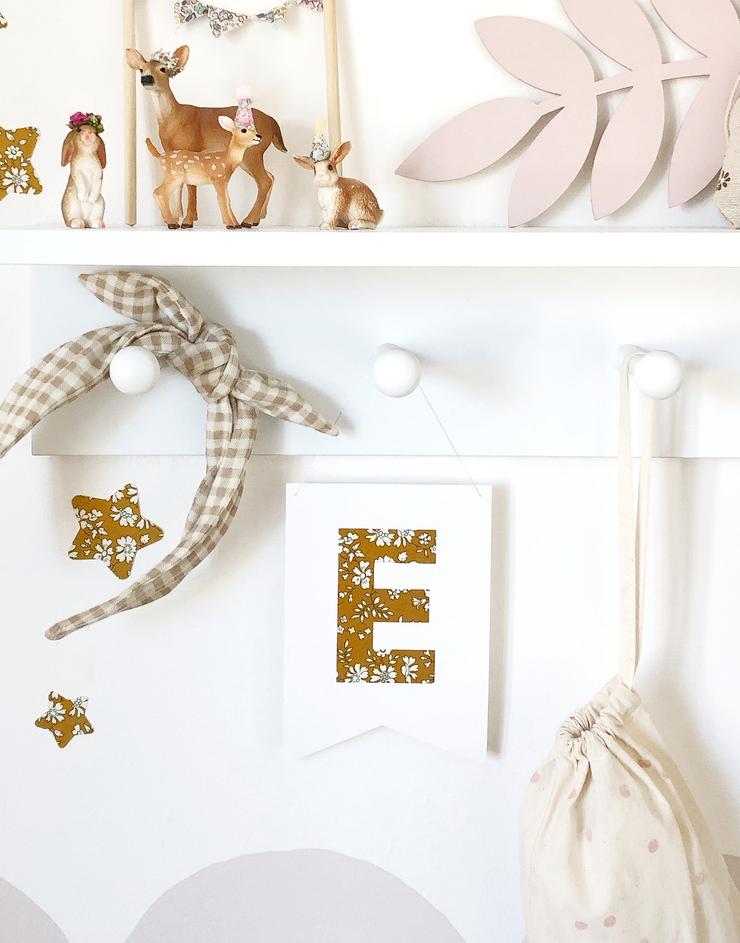 Child's bedroom shelf showing decor including mini monogram nursery flag in Liberty print Capel.