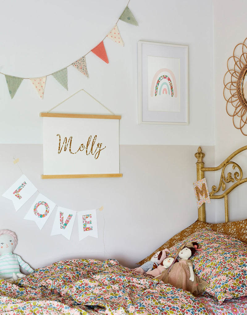 Children's bedroom gallery wall showing personalised name nursery art, rainbow print and bunting by The Charming Press